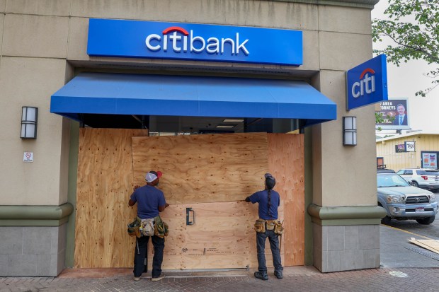 Workers board up windows of a bank before the start...